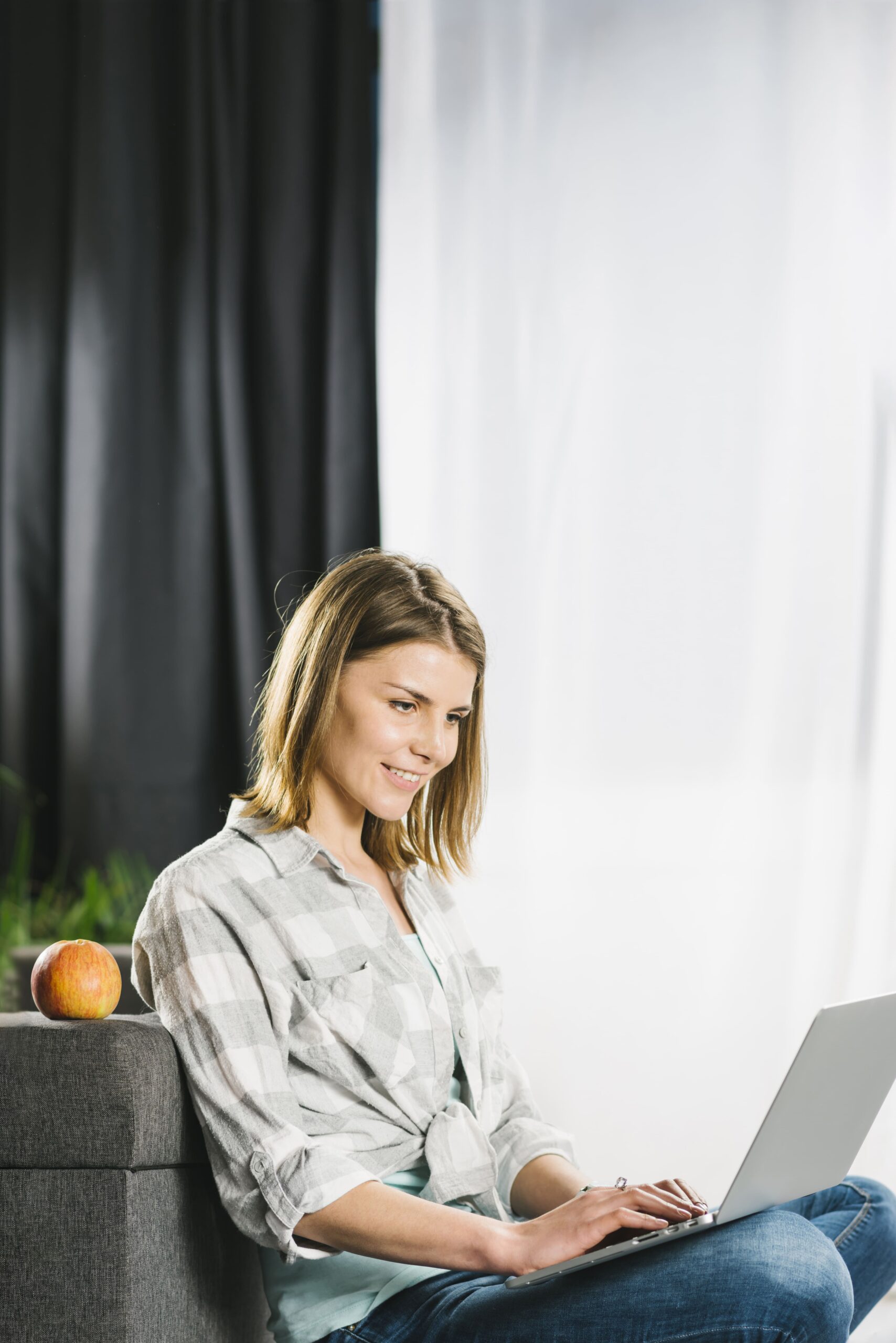 Mädchen sitzt auf der Couch mit einem Laptop